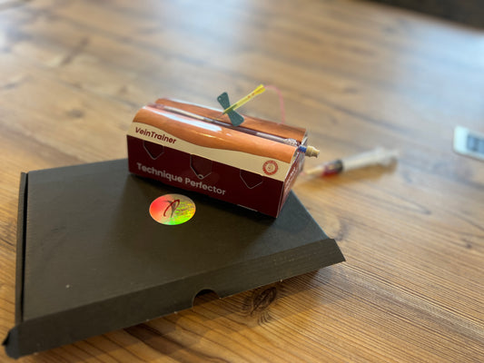 Small device labeled 'VeinTrainer Technique Perfector' VeinTrain flat-pack vein simulator for phlebotomy and cannulation training
VeinTrain flat-pack vein simulator for phlebotomy and cannulation training