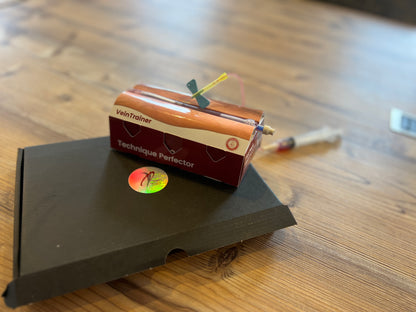 Small device labeled 'VeinTrainer Technique Perfector' VeinTrain flat-pack vein simulator for phlebotomy and cannulation training
VeinTrain flat-pack vein simulator for phlebotomy and cannulation training
